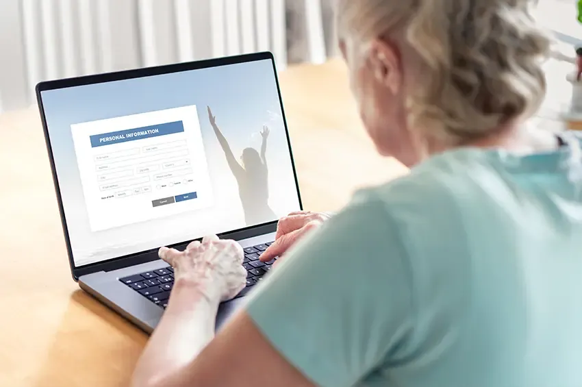 Ältere Frau bucht am Notebook einen Termin über ein Online-Formular